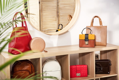 Photo of Collection of stylish woman's bags on wooden shelving unit indoors