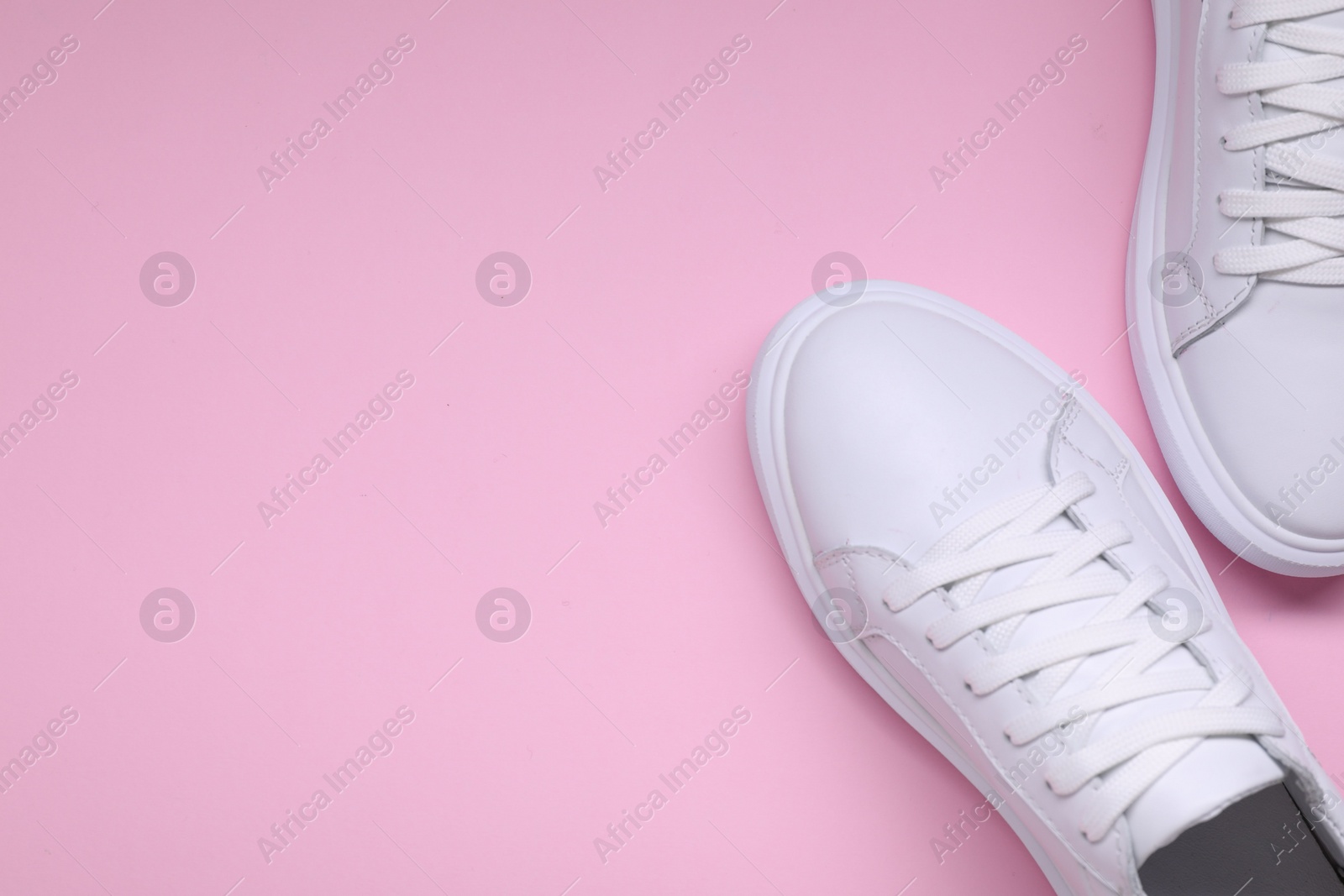 Photo of Pair of stylish white sneakers on pink background, top view. Space for text