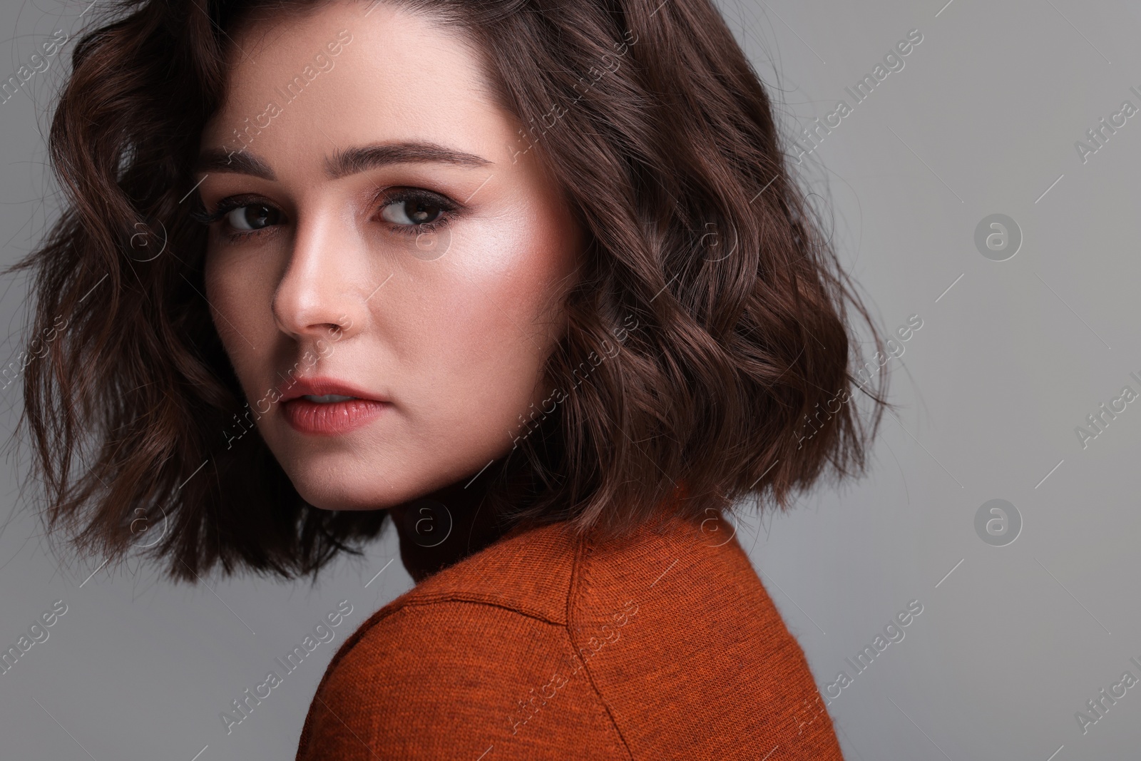 Photo of Beautiful young woman with wavy hairstyle on grey background