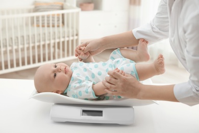 Photo of Doctor weighting baby on scales in light room