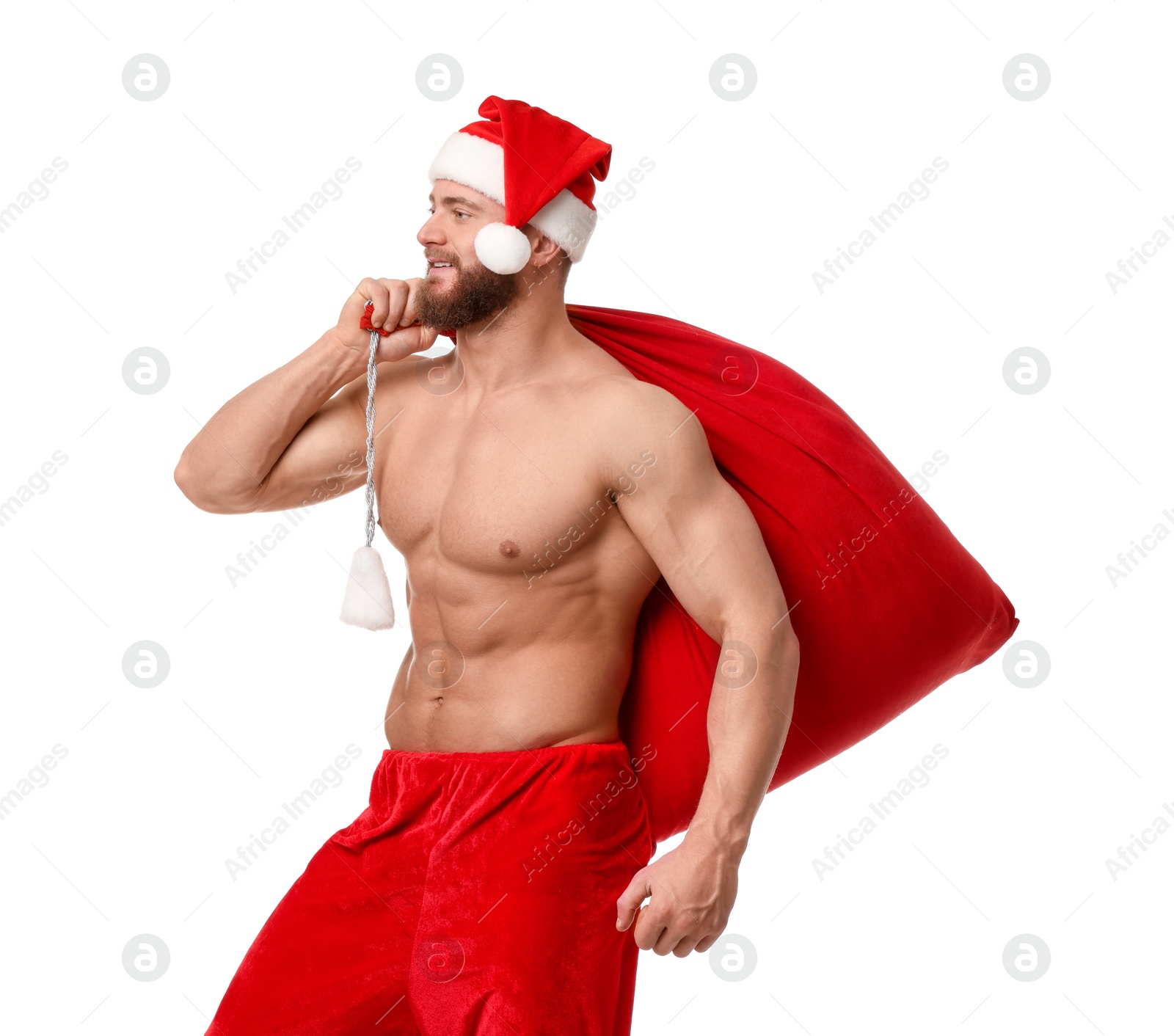 Photo of Muscular young man in Santa hat holding bag with presents on white background