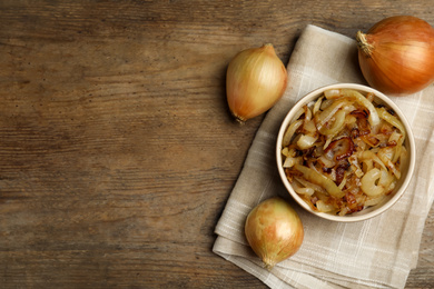 Photo of Tasty fried onion on wooden table, flat lay. Space for text