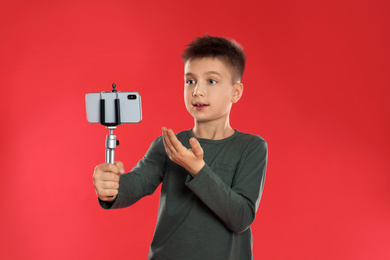 Cute little blogger recording video on red background