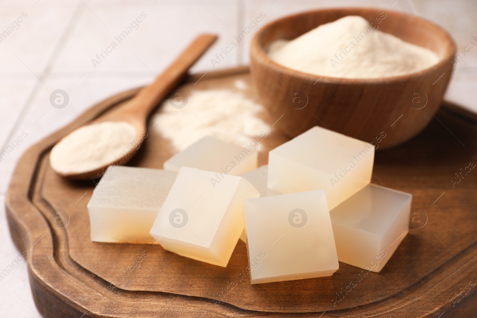 Photo of Agar-agar jelly cubes and powder on wooden board, closeup