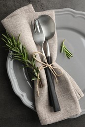 Stylish setting with cutlery and napkin on black table, top view