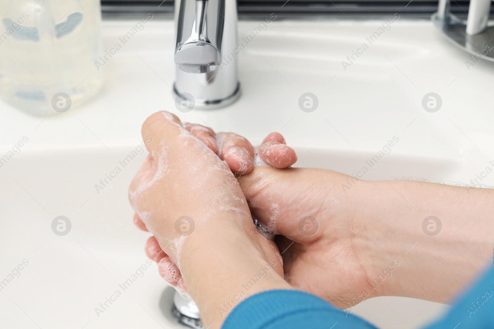 Photo of Man washing hands with soap over sink in bathroom, closeup