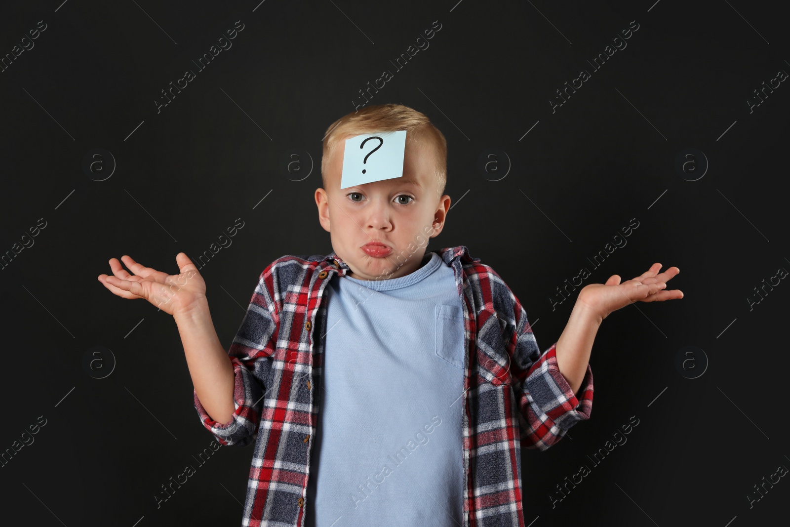 Photo of Confused boy with question mark sticker on forehead against black background