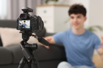 Photo of Teenage blogger explaining something while streaming at home, focus on camera