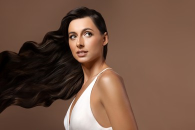 Image of Hair styling. Attractive woman with wavy long hair on brown background, space for text