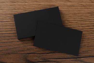 Photo of Blank black business cards on wooden background, flat lay. Mockup for design