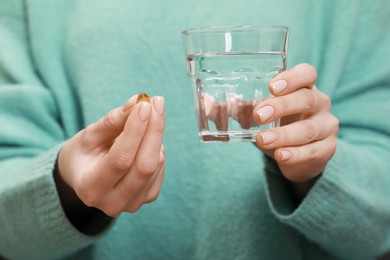 Photo of Woman holding glass of water and pill, closeup view