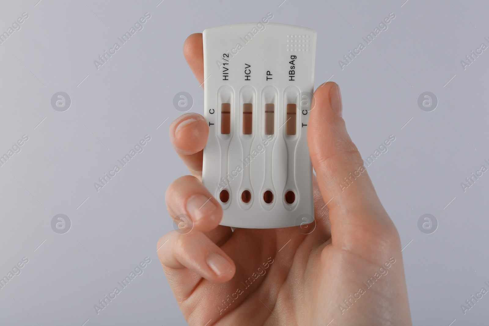 Photo of Woman holding disposable multi-infection express test on light grey background, closeup