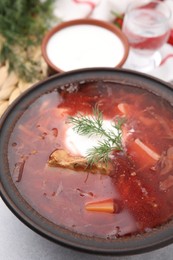 Photo of Tasty borscht with sour cream in bowl on grey table, closeup