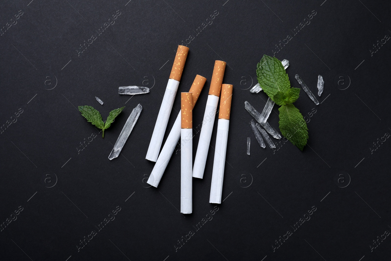 Photo of Cigarettes, menthol crystals and mint on black background, flat lay