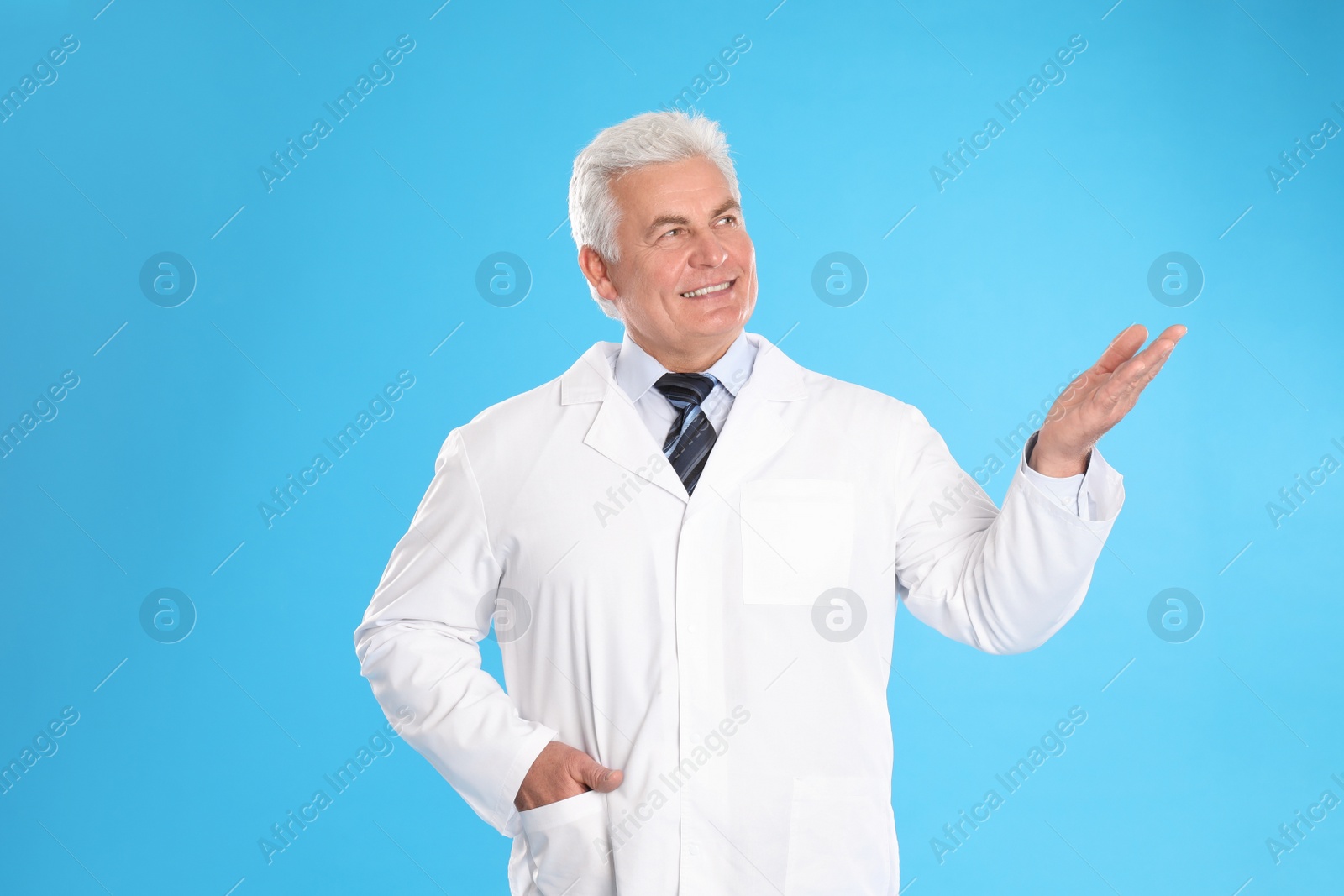 Photo of Happy senior man in lab coat on light blue background