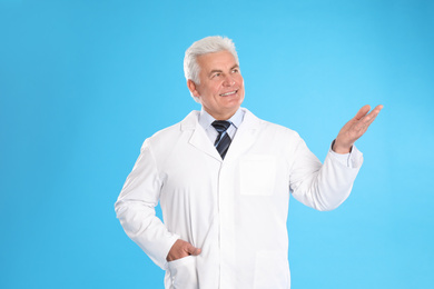 Photo of Happy senior man in lab coat on light blue background
