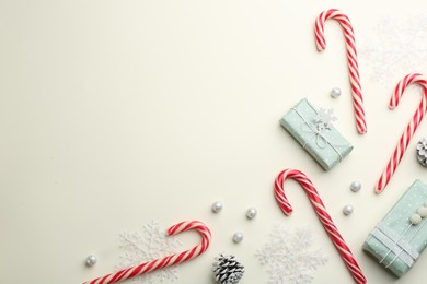Photo of Flat lay composition with candy canes and Christmas decor on beige background. Space for text