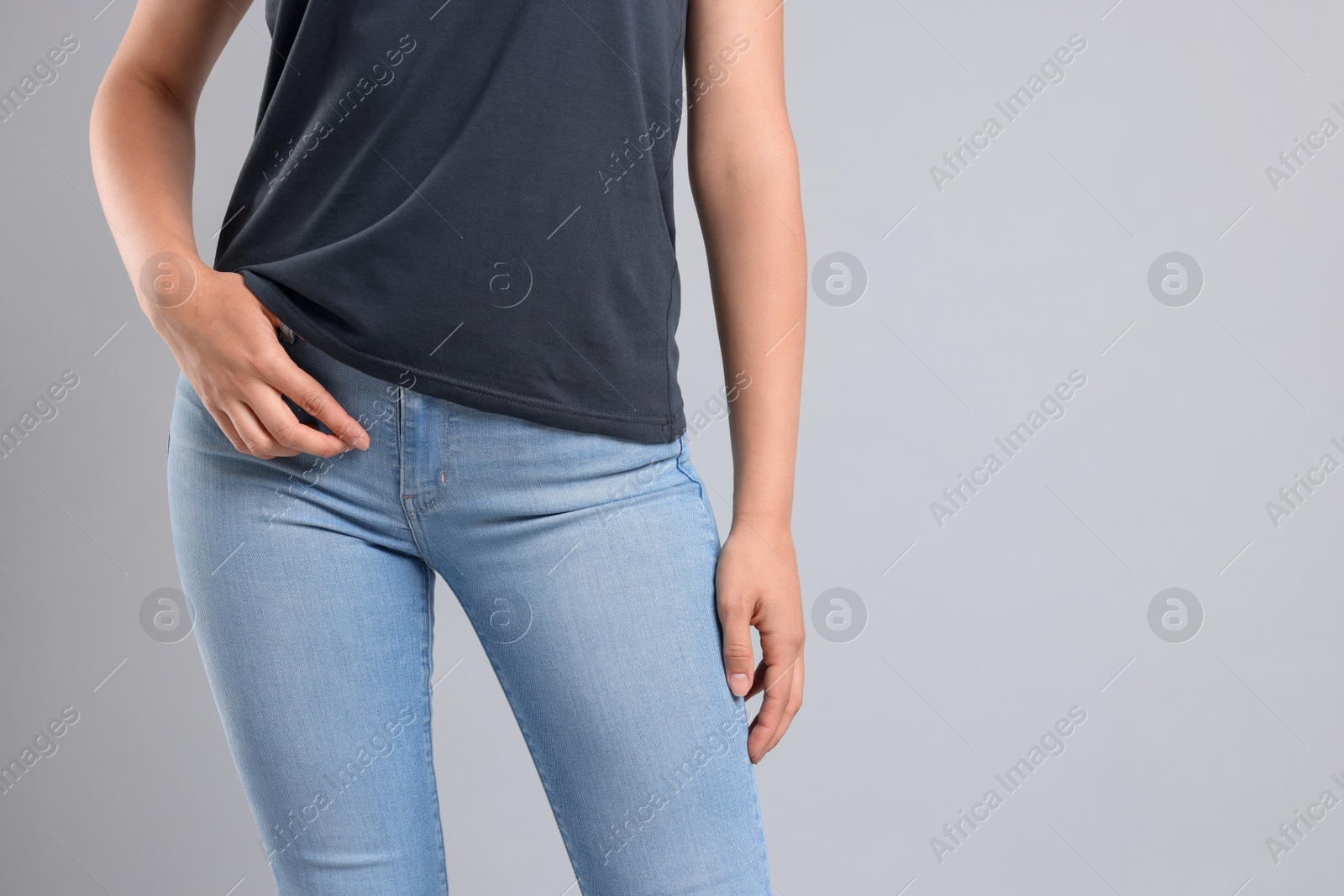 Photo of Woman wearing stylish jeans on light gray background, closeup. Space for text
