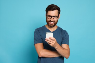 Photo of Happy man looking at smartphone on light blue background