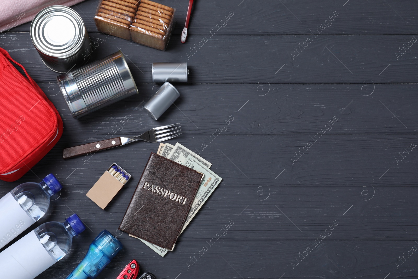 Photo of Earthquake supply kit on black wooden table, flat lay. Space for text