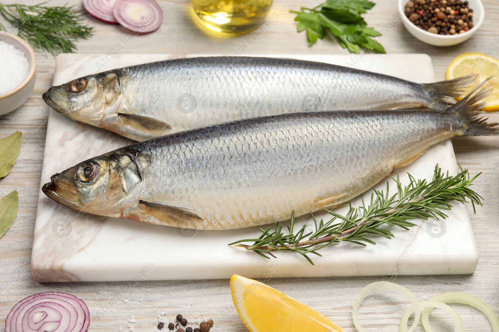 Photo of Delicious salted herrings and different ingredients on wooden table