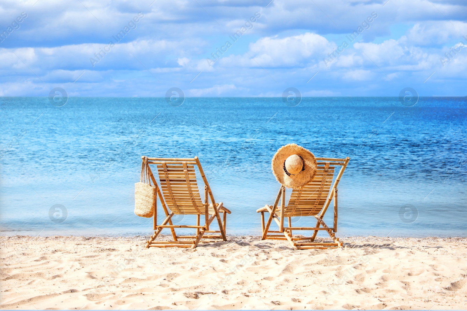 Image of Empty wooden sunbeds on sandy beach near sea on sunny day