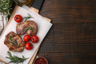 Delicious fried meat with rosemary, tomatoes and spices on wooden table, flat lay. Space for text
