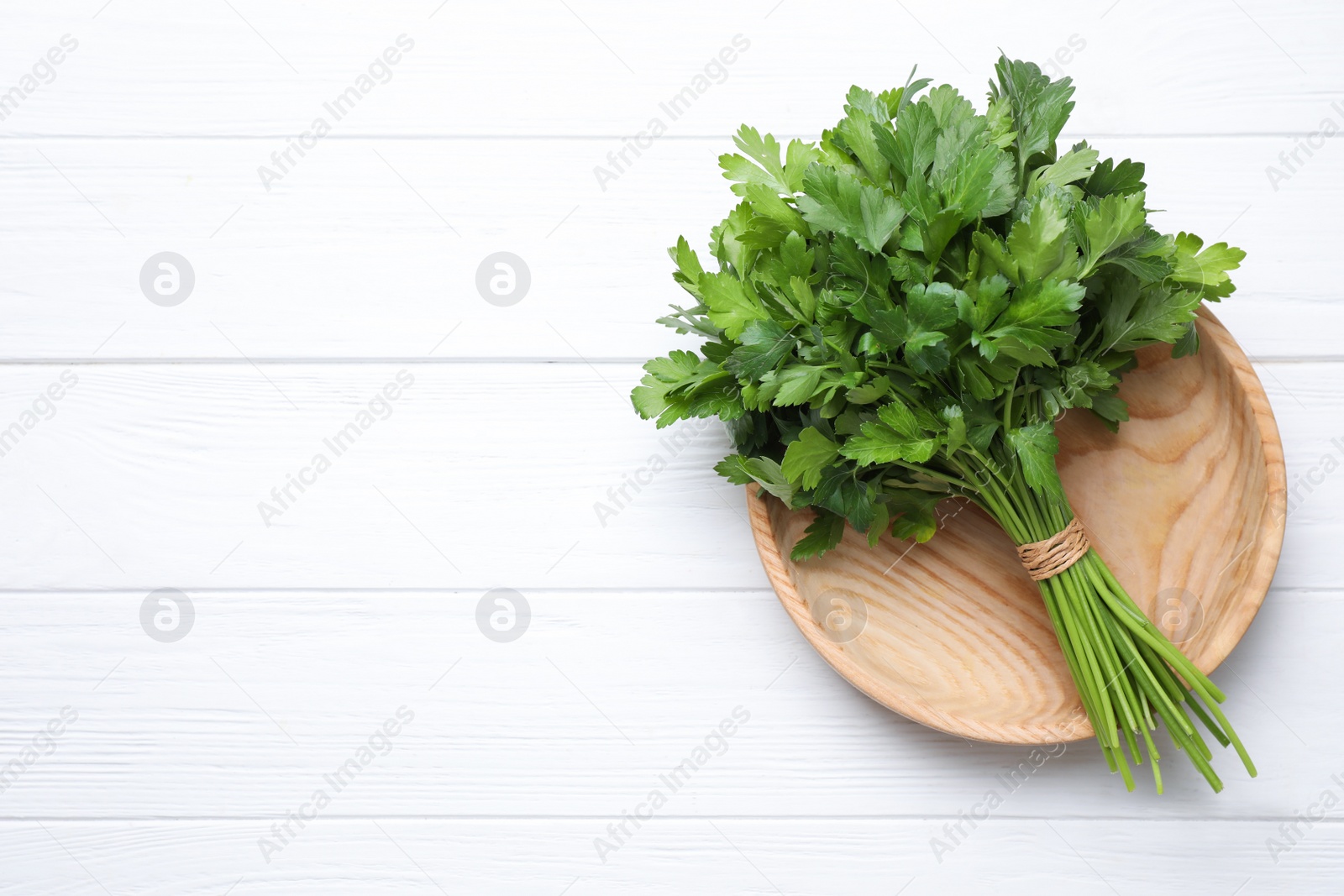 Photo of Bunch of fresh green parsley on white wooden table, top view. Space for text