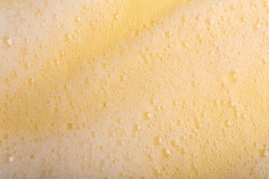 Photo of White fluffy foam on yellow background, top view