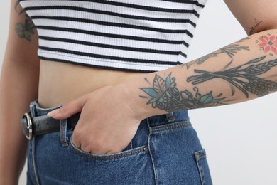 Woman with cool tattoos on gray background, closeup