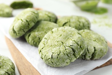Photo of Board with tasty matcha cookies on white table, selective focus