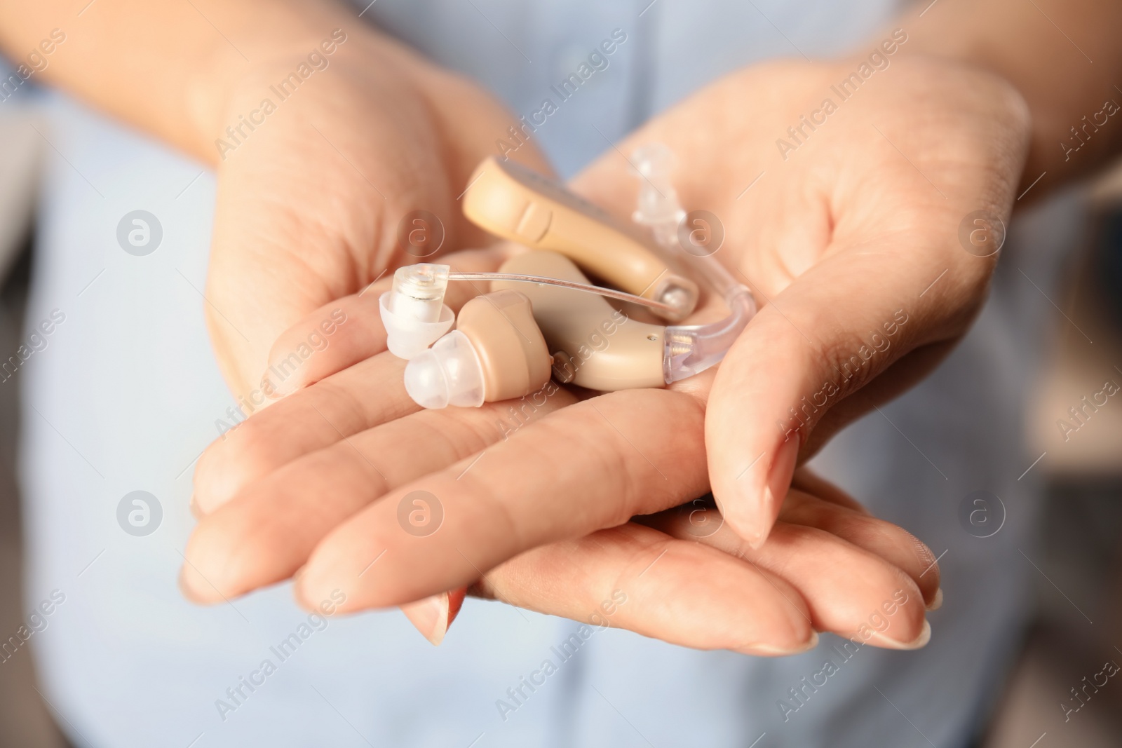 Photo of Woman holding hearing aids, closeup of hands