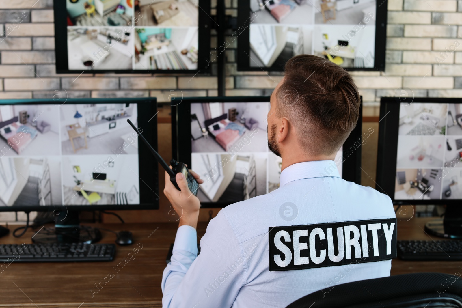 Photo of Male security guard with portable transmitter monitoring modern CCTV cameras indoors