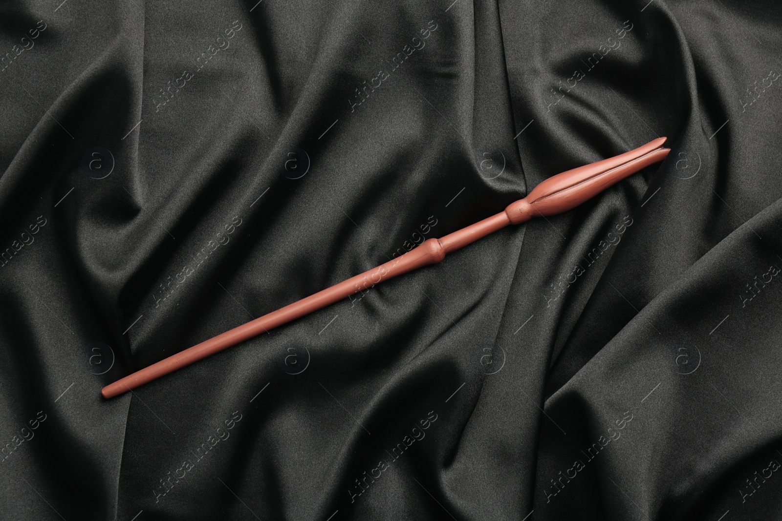 Photo of One magic wand on black fabric, top view