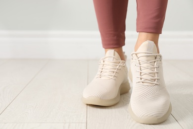 Woman in comfortable stylish sport shoes indoors, closeup. Space for text