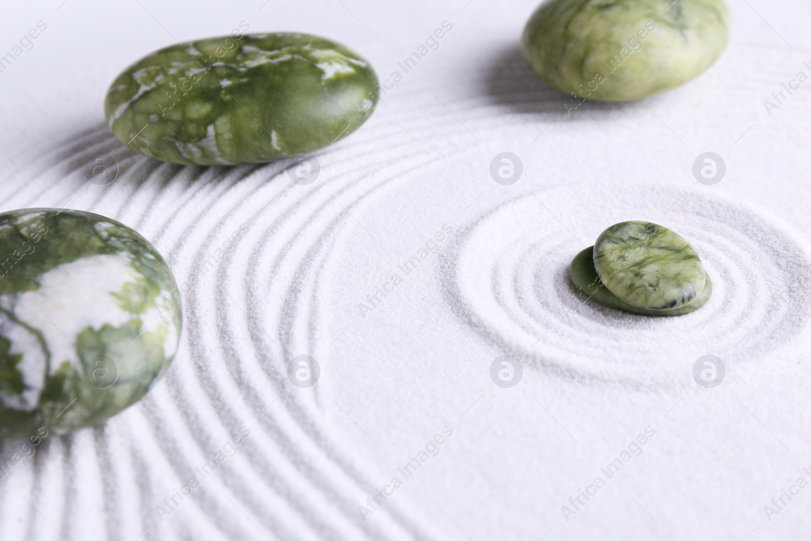 Photo of Zen concept. Stones and pattern on white sand, closeup