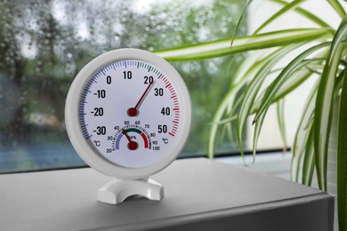 Round mechanical hygrometer on book near window