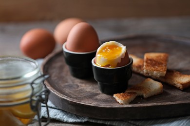 Soft boiled chicken eggs with toasted bread on wooden table