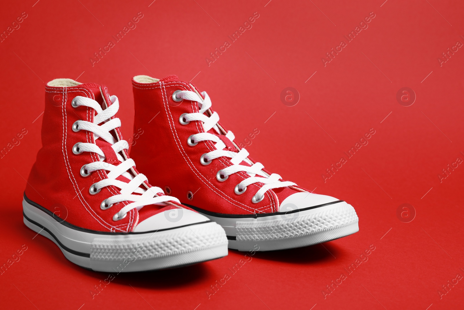 Photo of Pair of new stylish sneakers on red background