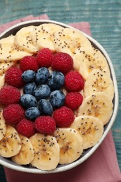 Photo of Tasty breakfast dish with berries, banana and chia seeds on wooden table, top view