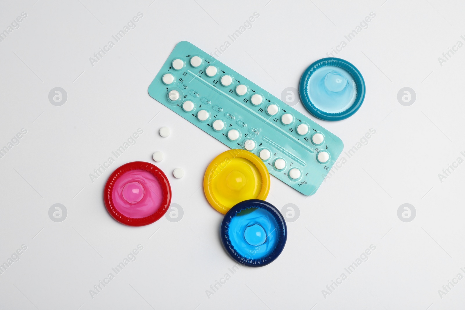 Photo of Condoms and birth control pills on light grey background, flat lay. Safe sex concept