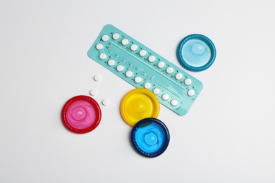 Condoms and birth control pills on light grey background, flat lay. Safe sex concept