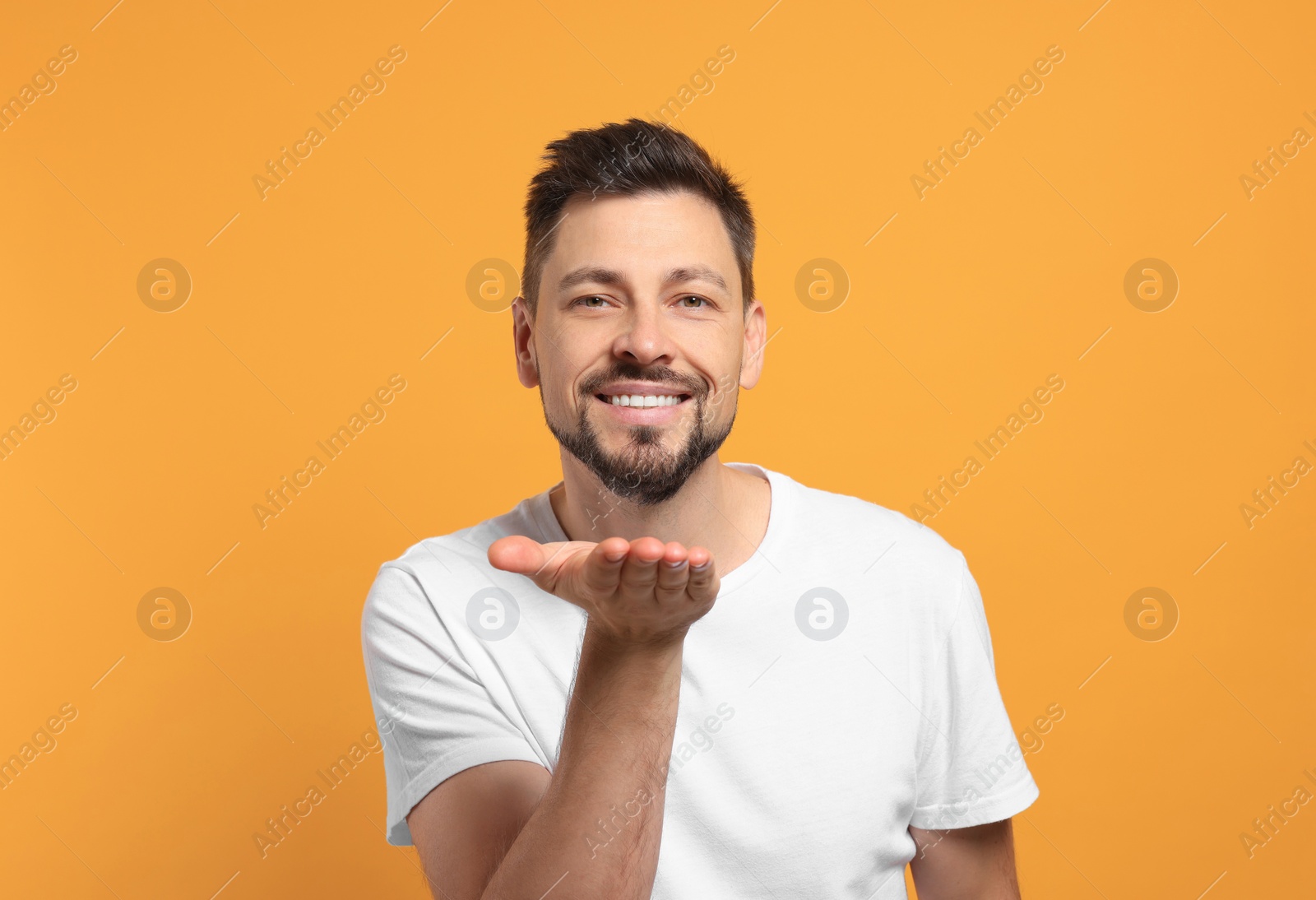 Photo of Handsome man with charming smile on orange background