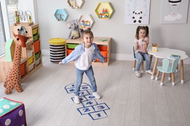 Photo of Cute little girls playing hopscotch at home