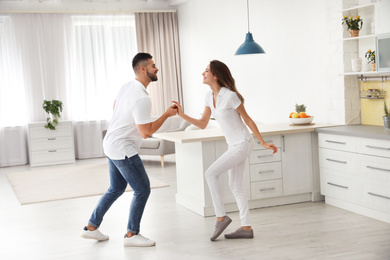 Photo of Lovely young couple dancing in kitchen at home