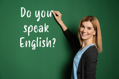 Beautiful teacher writing question DO YOU SPEAK ENGLISH on chalkboard