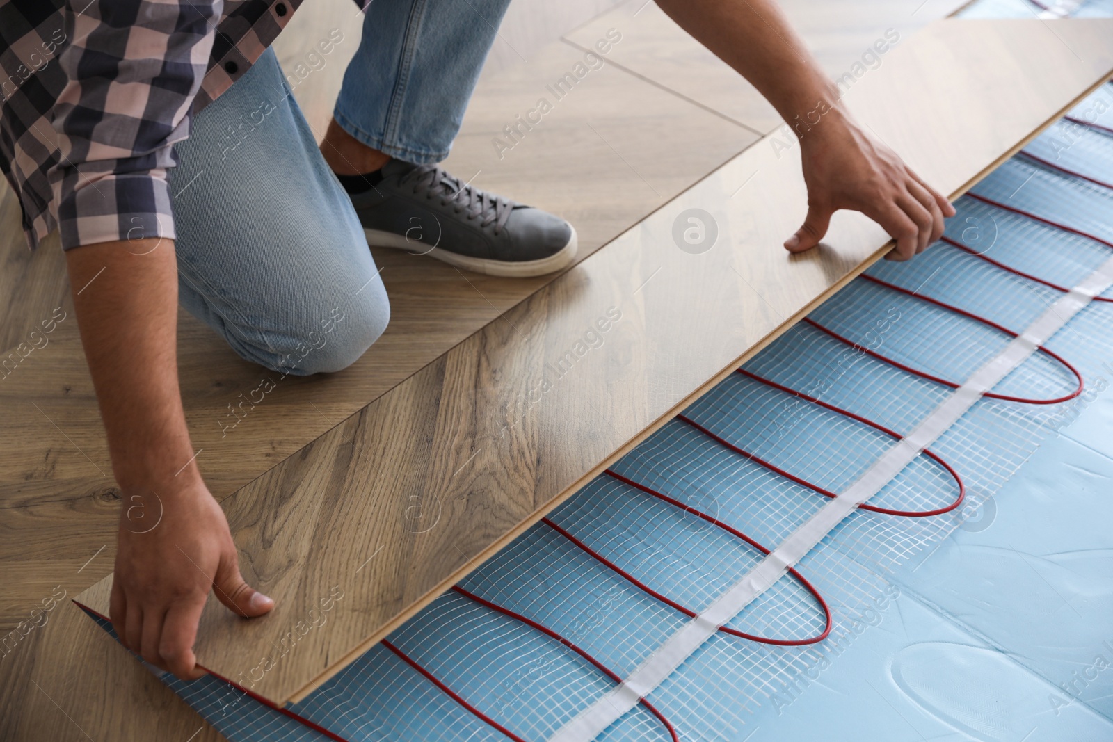 Photo of Professional contractor installing underfloor trace heating system indoors, closeup