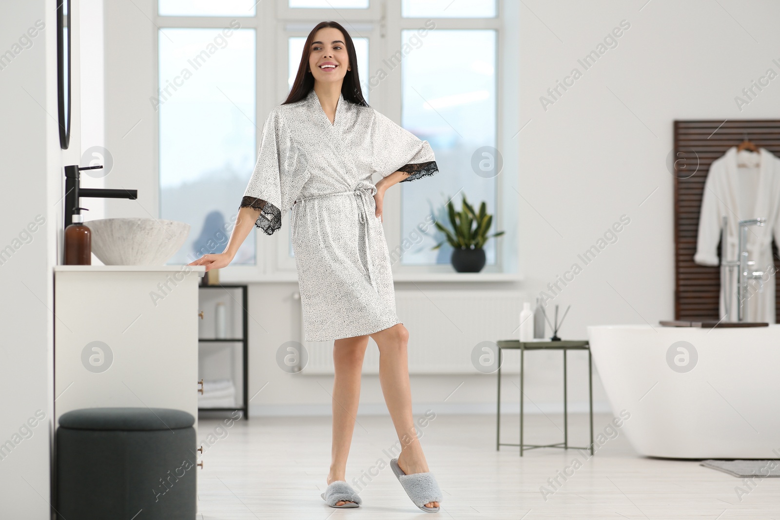 Photo of Beautiful happy woman wearing stylish bathrobe in bathroom