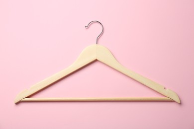 Wooden hanger on pink background, top view