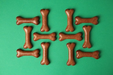 Photo of Bone shaped dog cookies on green background, flat lay